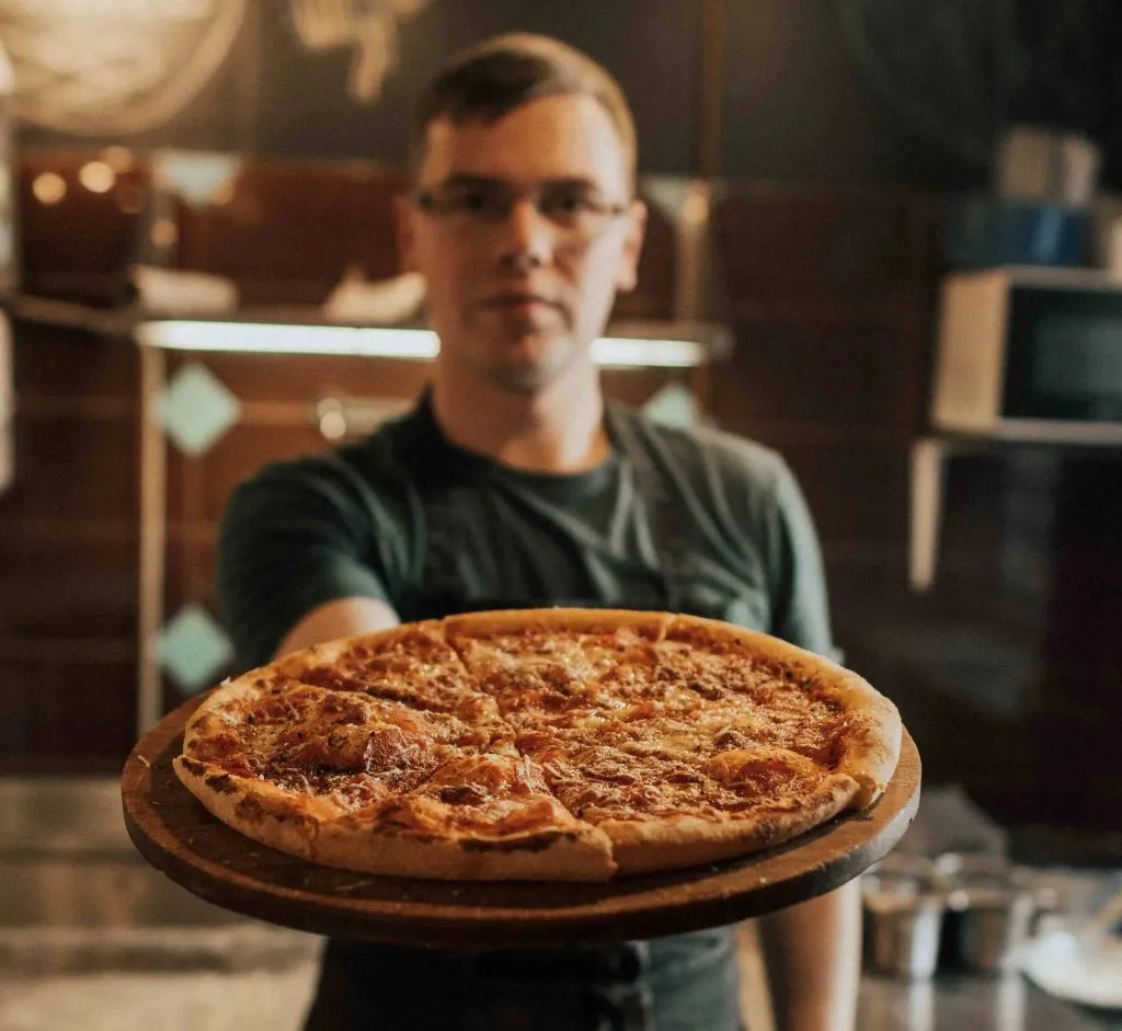 Chef holding out a pizza